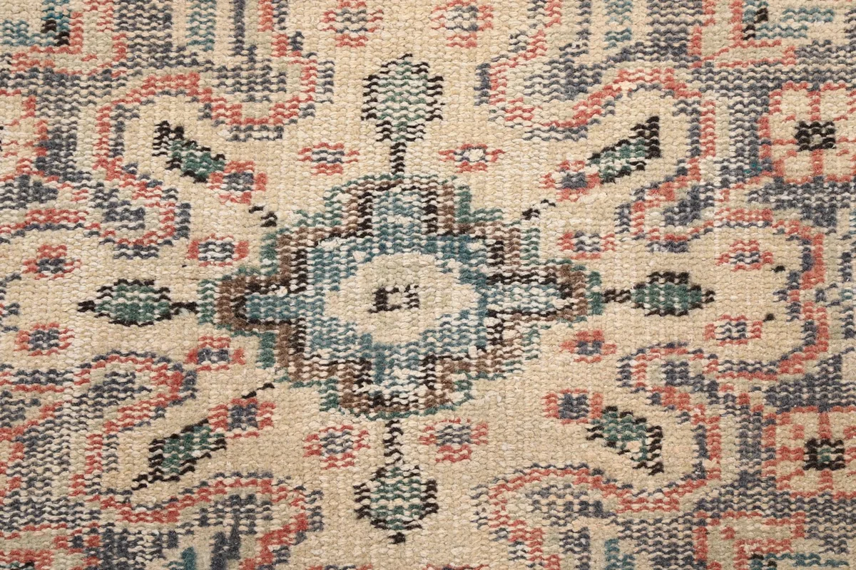 Macro detail of the hand-knotted wool pile, showing the intricate gray, ivory, and blue threads