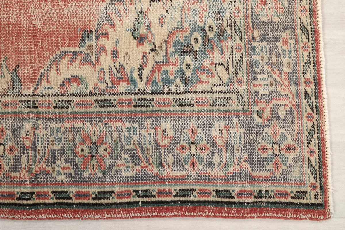 Detail of the rug's gray and ivory border pattern with subtle rose and blue accents