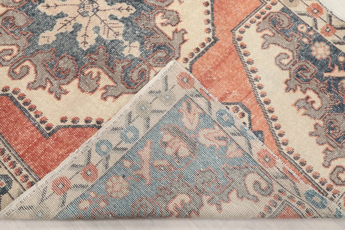 Folded corner of the rug revealing the cotton foundation and reverse side