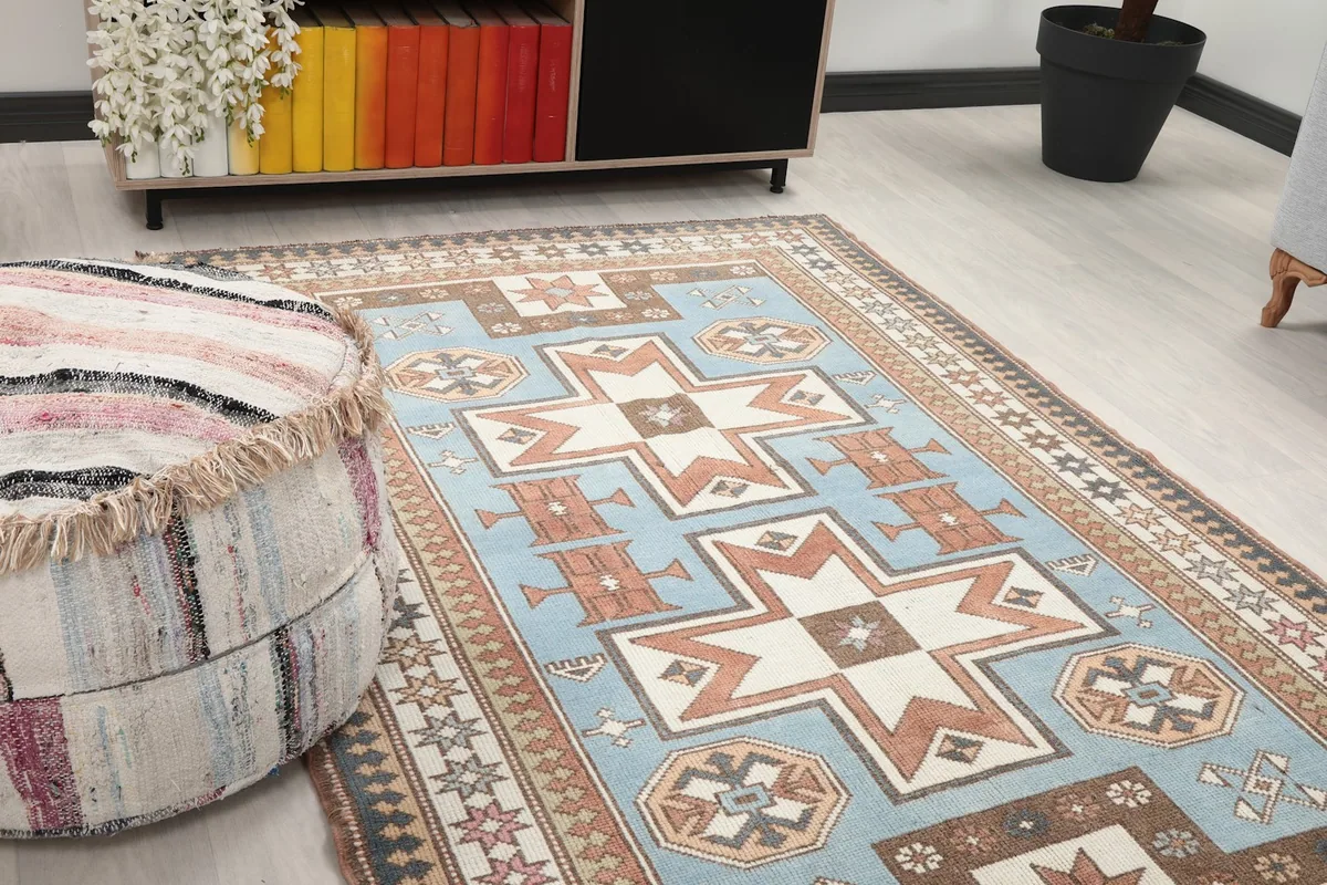 Close-up view of the rug's blue field and geometric motifs next to a striped ottoman