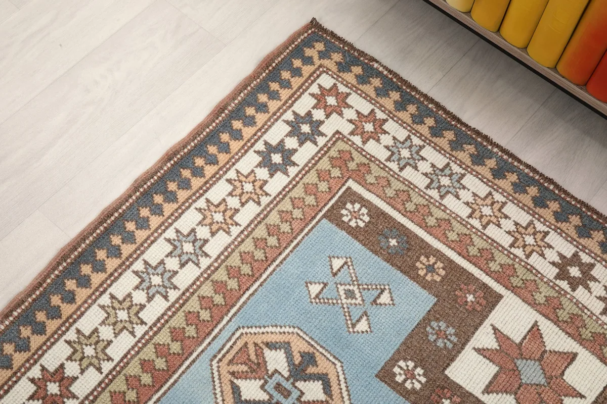 Corner detail of the rug, showing the blend of blue, rust, ivory, and brown colors in the border