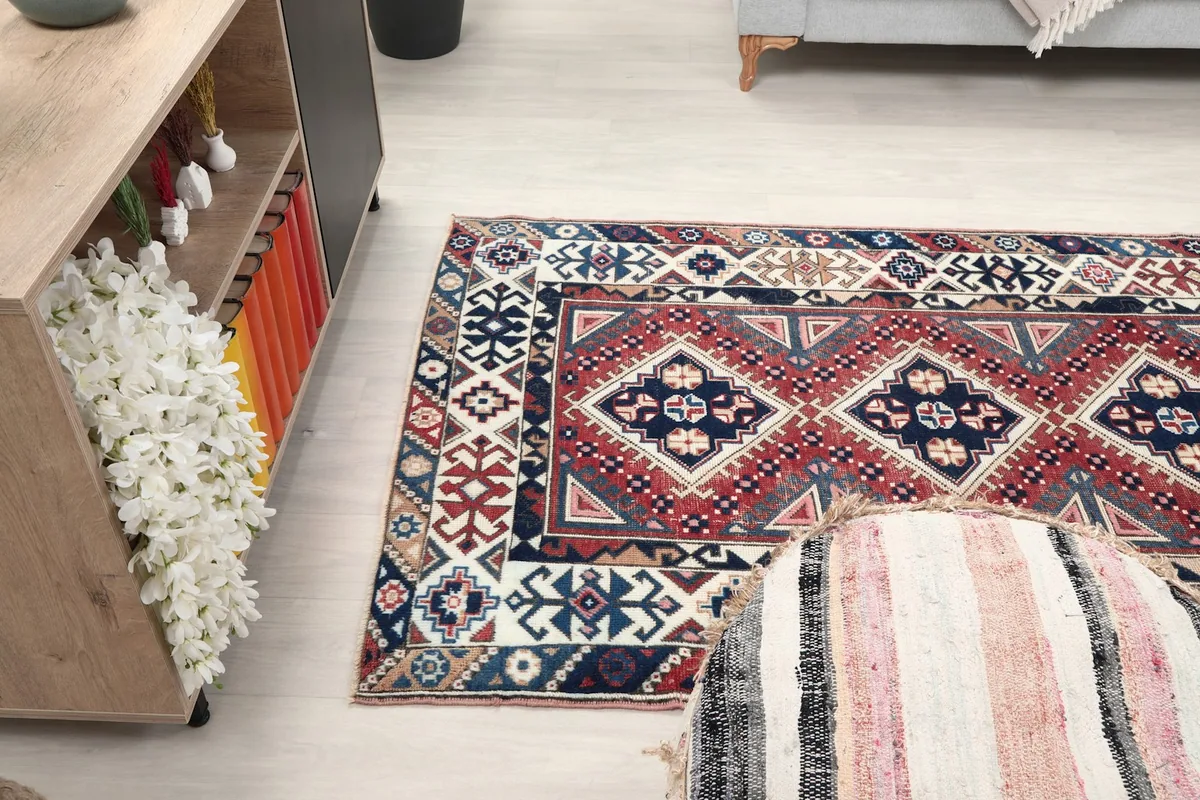 Rug placed in a room, showing its size in relation to a sofa and cabinet from an angle