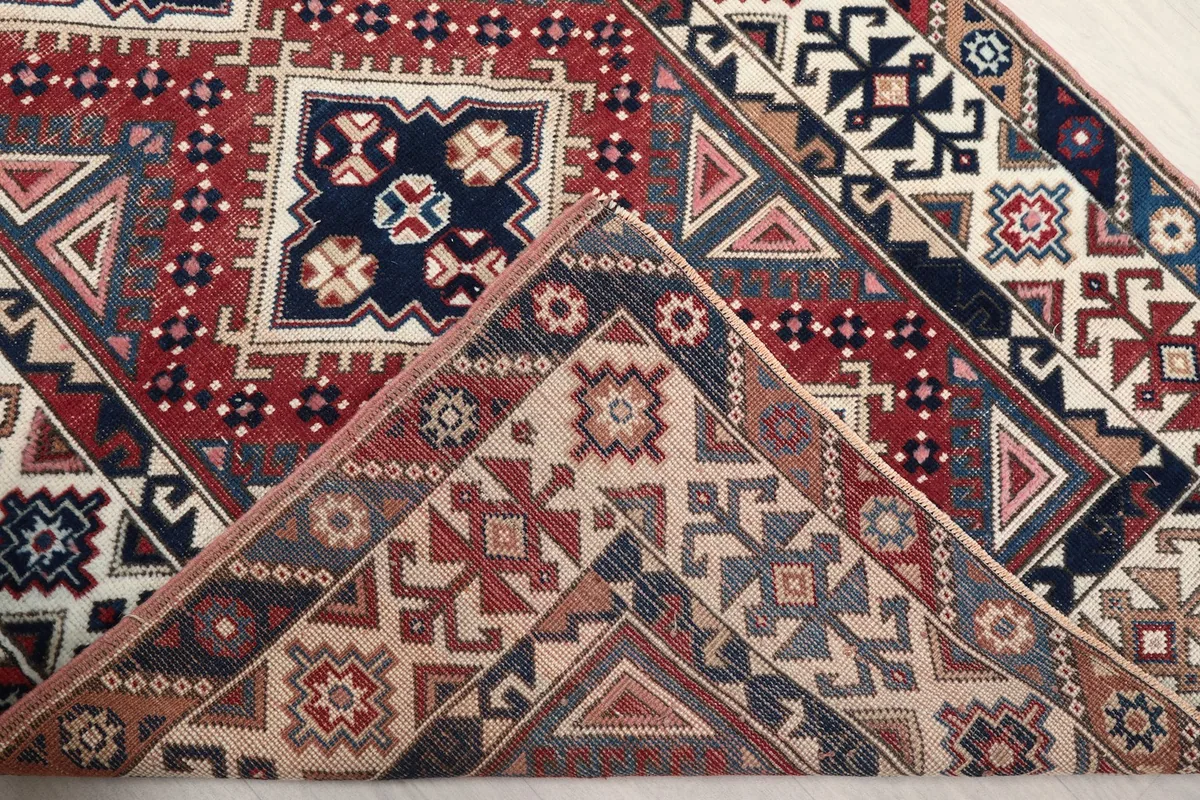 Folded corner of the rug revealing the wool pile and cotton foundation texture