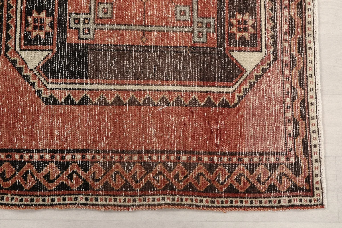 Detailed view of the rug's border pattern and corner, highlighting the aged texture.