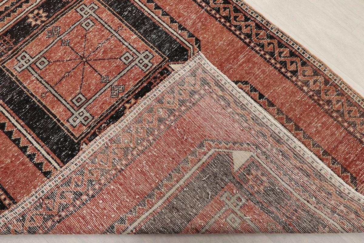 Folded corner of the rug revealing the hand-knotted construction and cotton foundation.