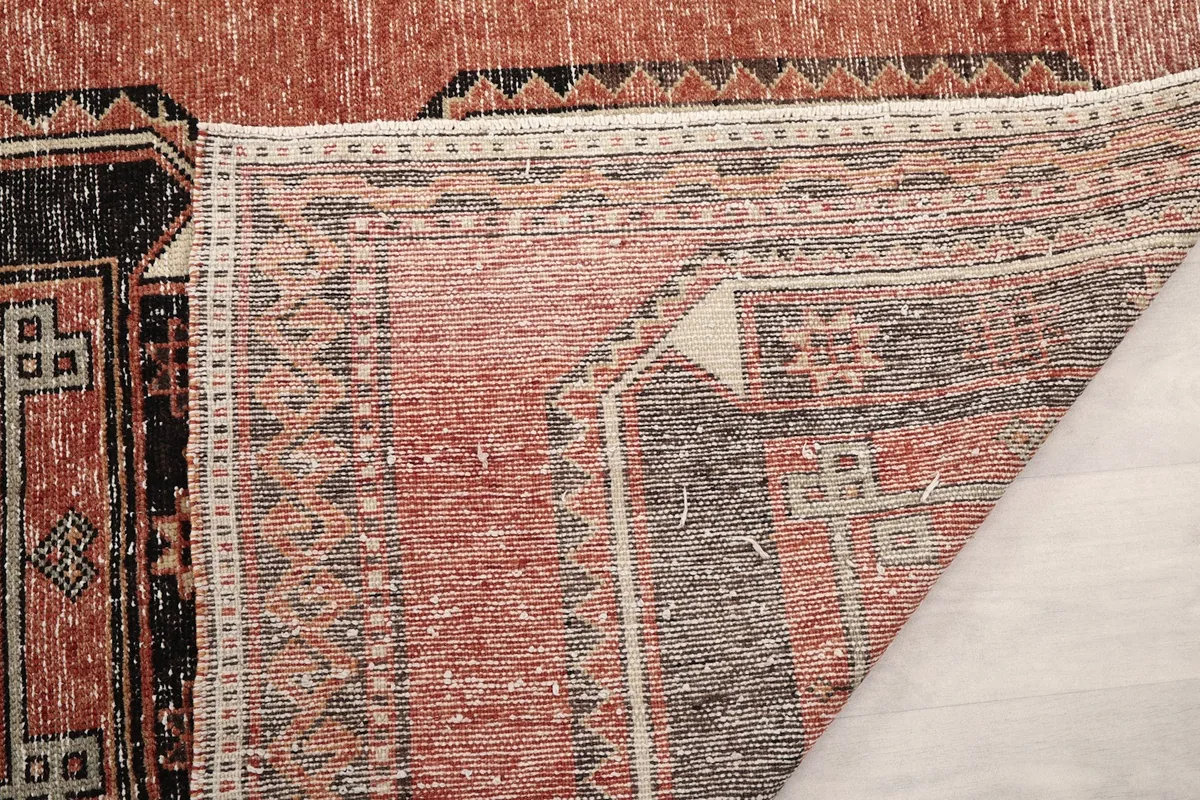View of the underside of the rug, showing the tight knotting and vintage wear on the back.