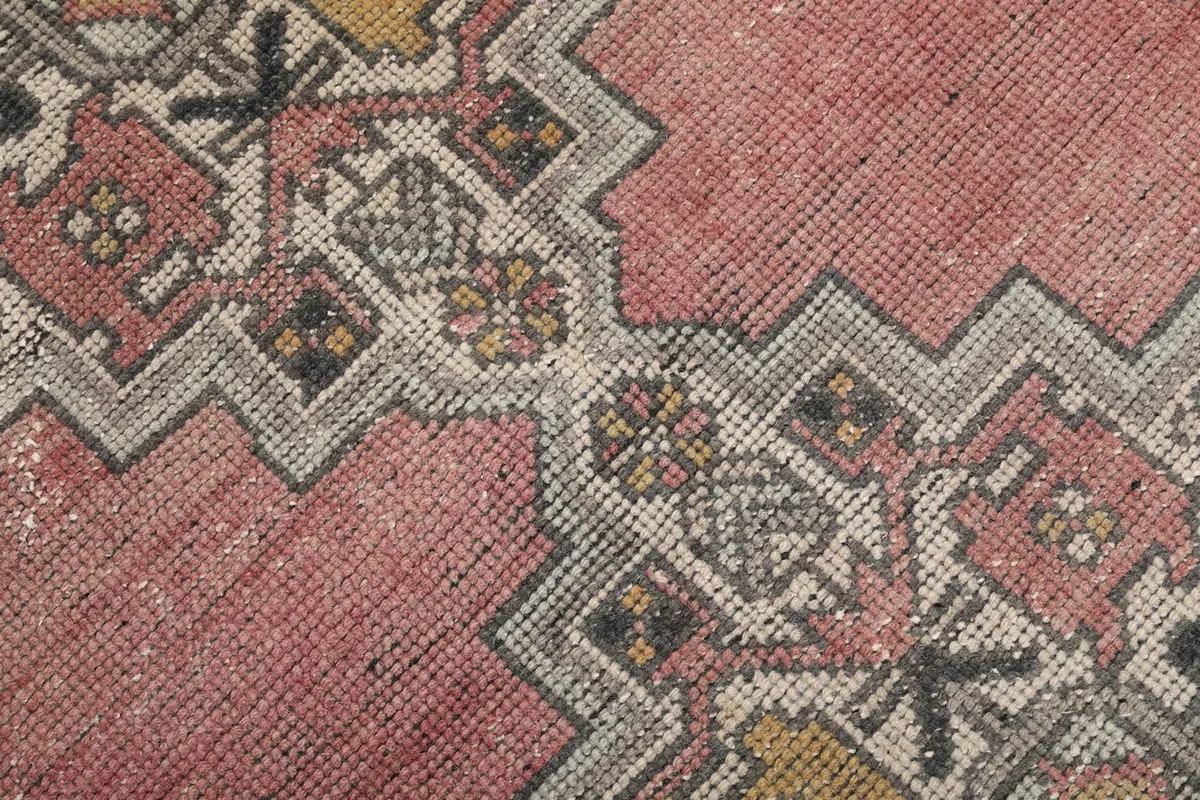 Close-up of the hand-knotted wool pile, showing the texture and colors within the geometric patterns.