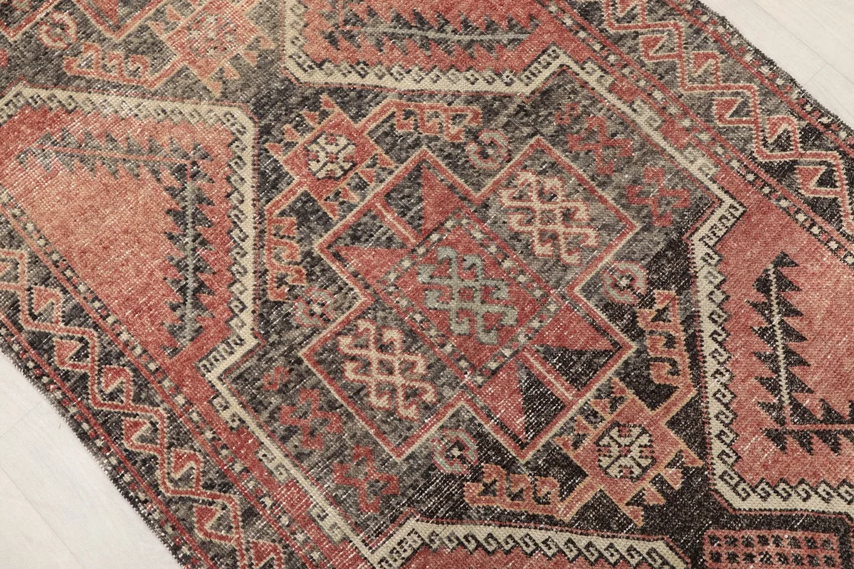 Close-up detail of the central charcoal and rose geometric medallion on the runner rug