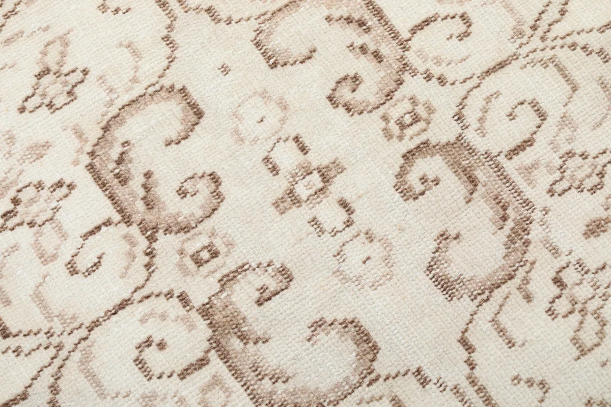 Extreme close-up of the low pile and texture of the hand-knotted wool, showing tan details