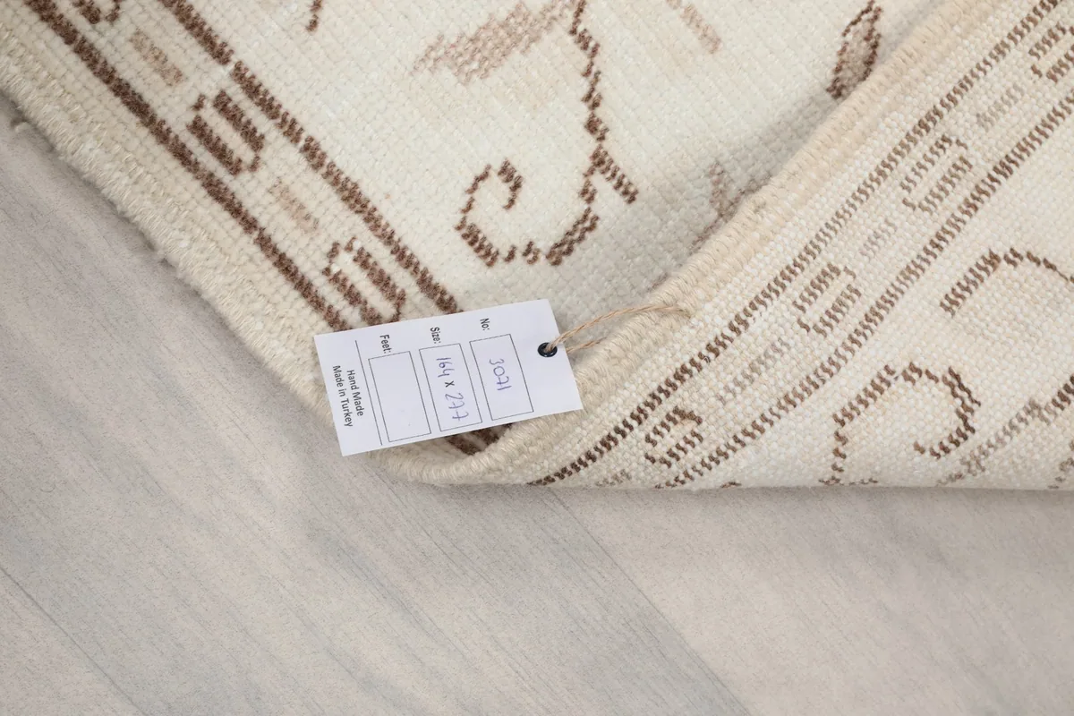Close-up of the rug's corner with the product tag showing size 5'5" x 9'1" and material details
