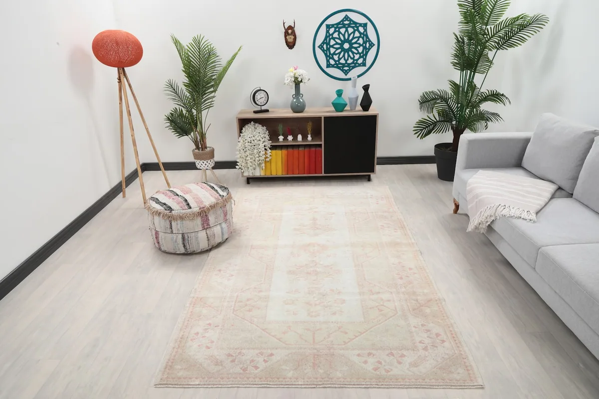 Cream and rose medallion rug in a living room setting with a sofa and ottoman