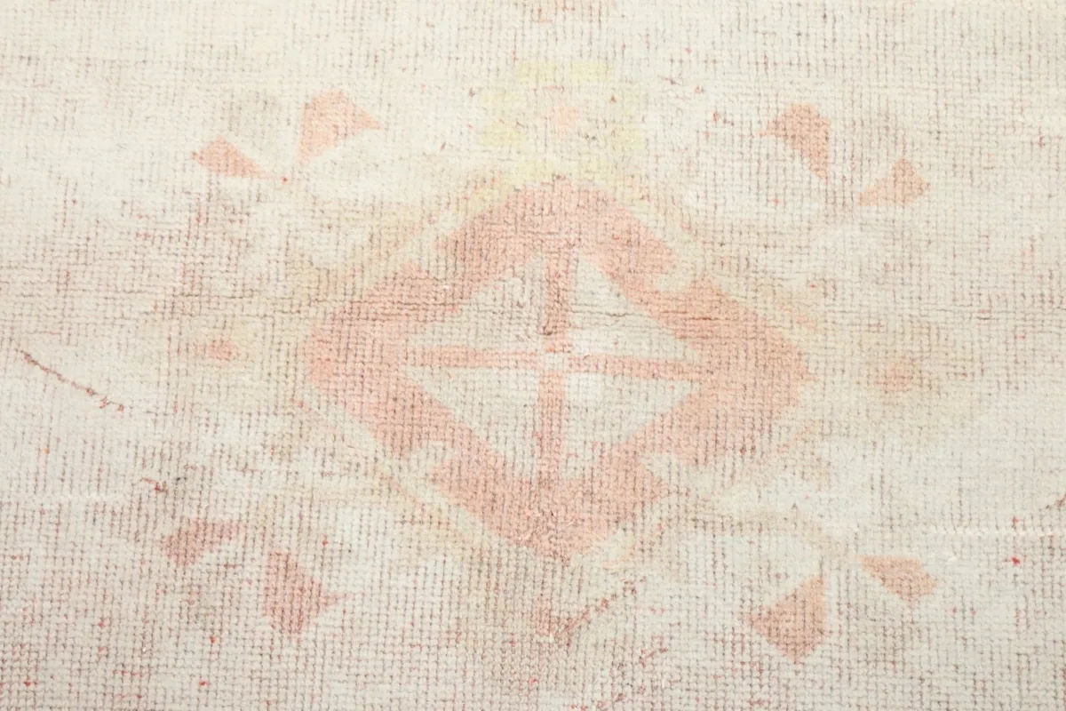 Close-up of the faded rose central medallion and subtle patterns on the rug