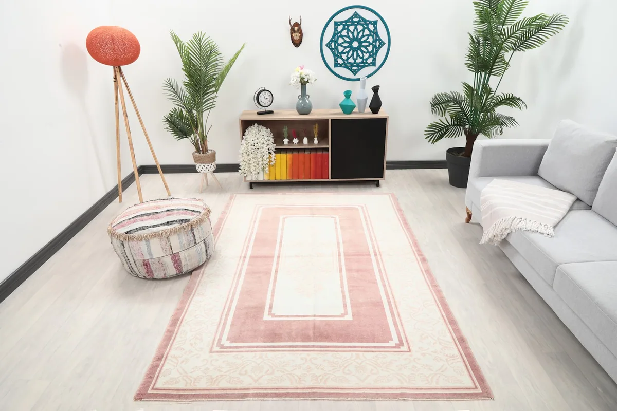 Vintage rose and ivory rug displayed in a bright living room setting with a sofa and plants