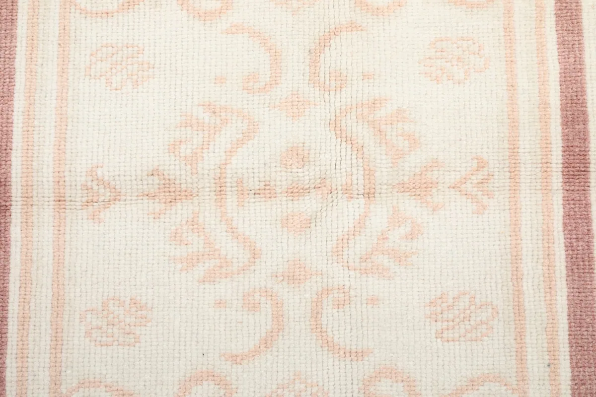 Close-up of the subtle floral design within the central ivory panel of the rug