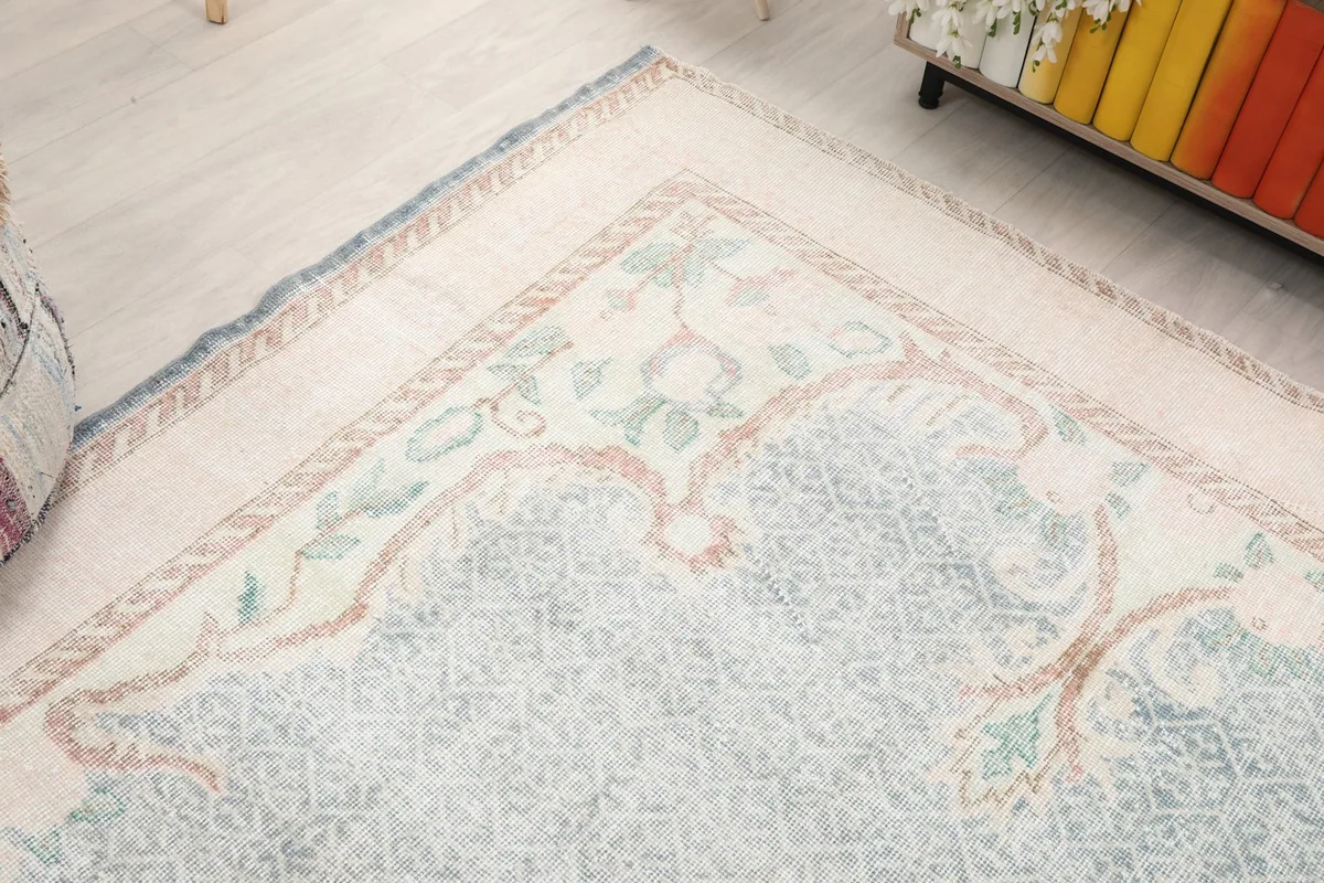 Corner view of the rug showing the subtle blue fringe and the decorative border elements