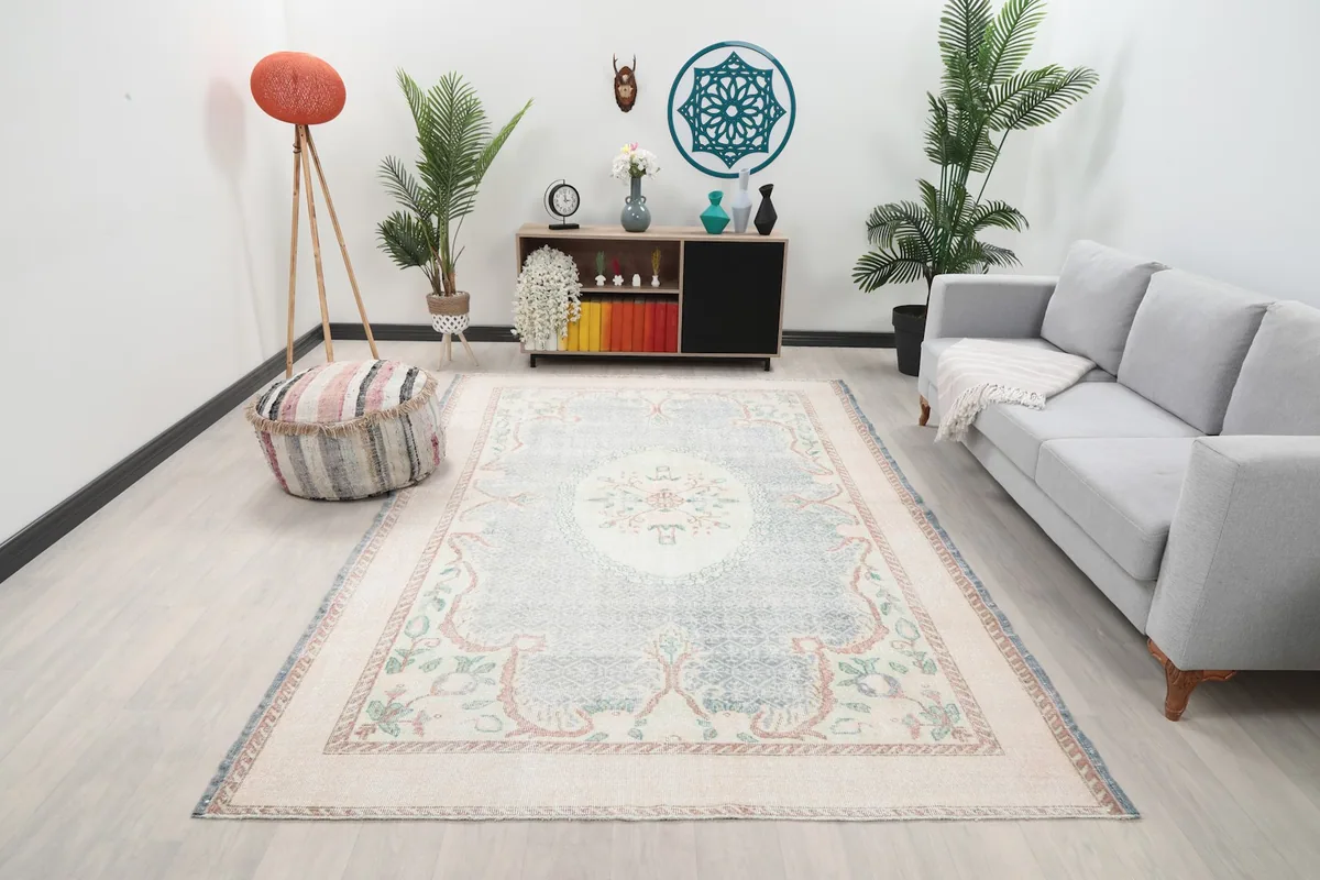 Vintage Anatolian rug displayed in a living room setting with a gray couch and decorative plants