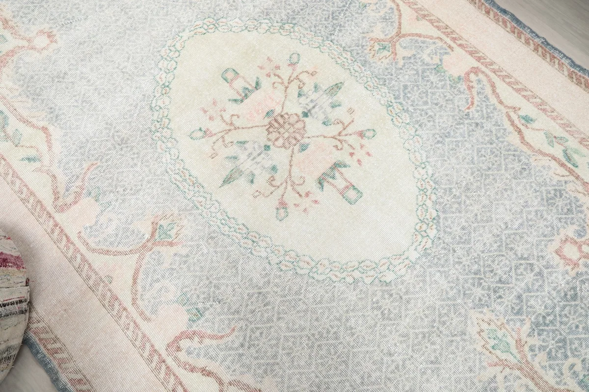 Close-up of the central ivory floral medallion against the faded blue field of the rug