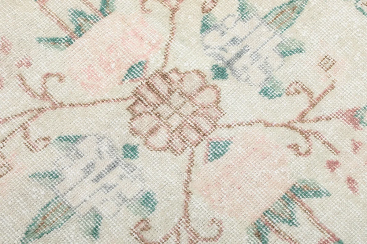 Detailed view of the intricate floral pattern and rose and green colors within the rug's medallion