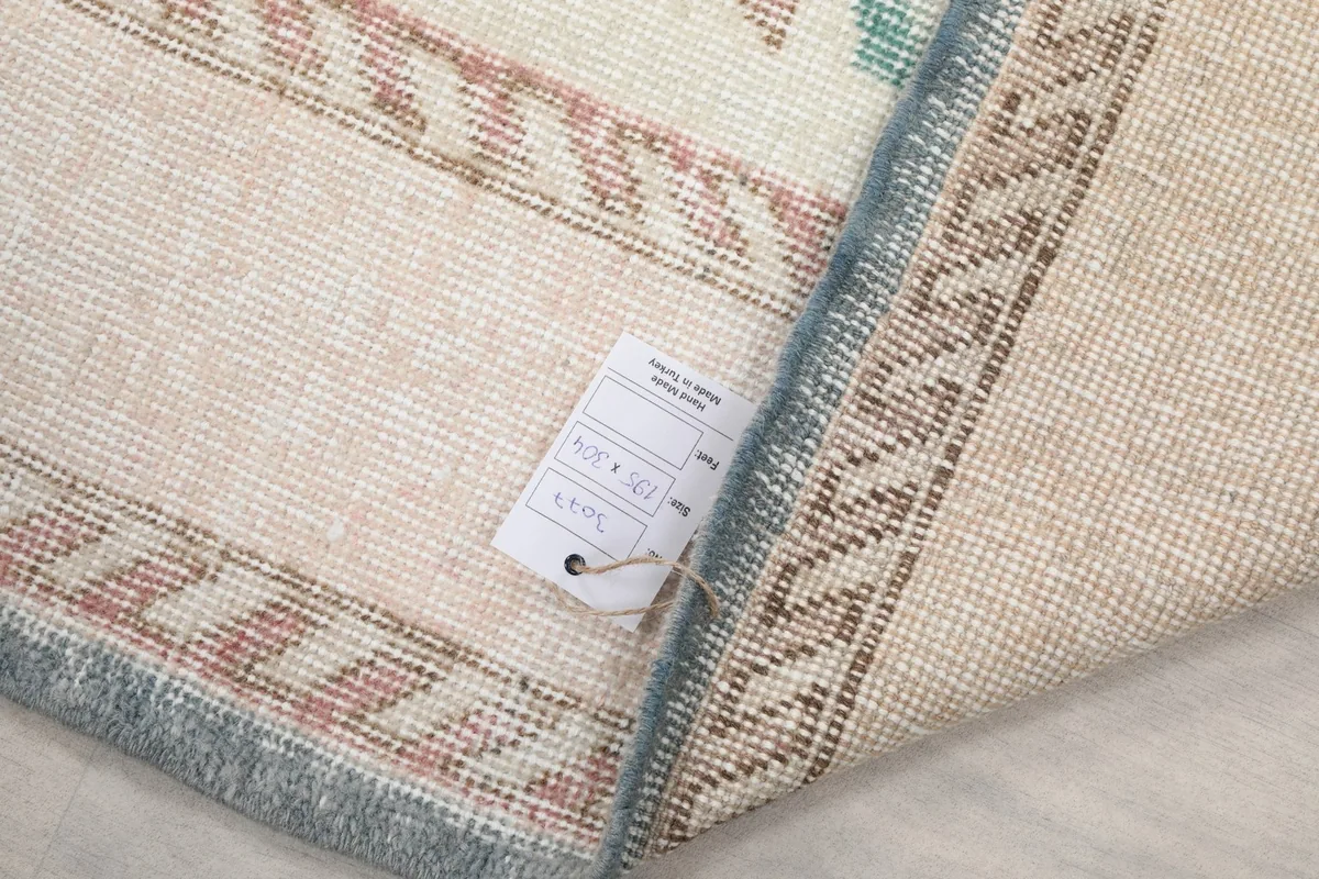 Underside of the rug with a product tag, displaying the tight hand-knotted cotton foundation