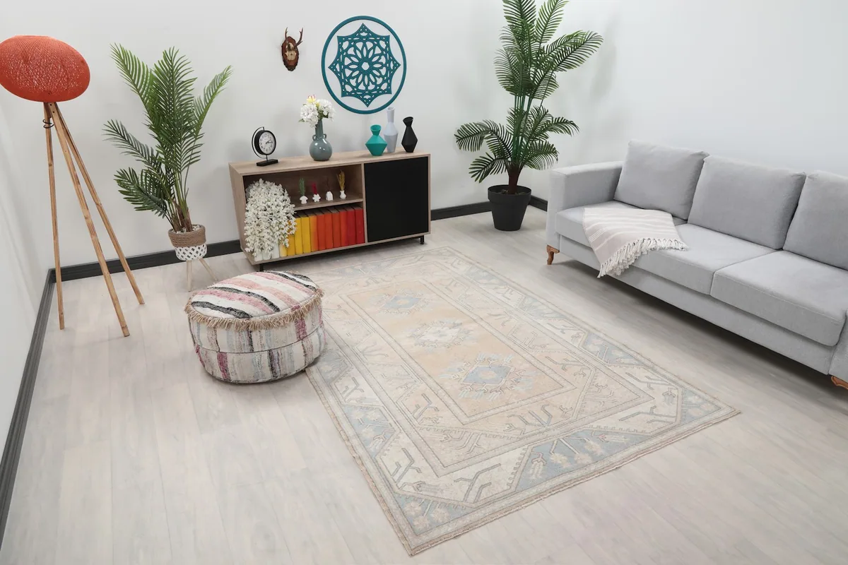 Angle view of the beige and blue tribal rug in a room, showing its placement on light flooring