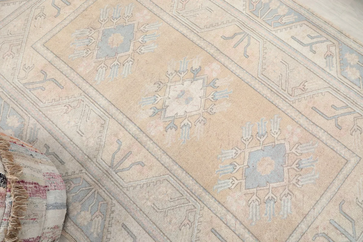 Overhead diagonal view of the vintage Anatolian rug, highlighting its central beige field and blue patterns