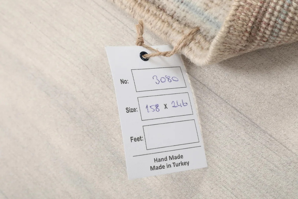 Product tag indicating the rug's dimensions in centimeters (158x246) and 'Hand Made in Turkey'