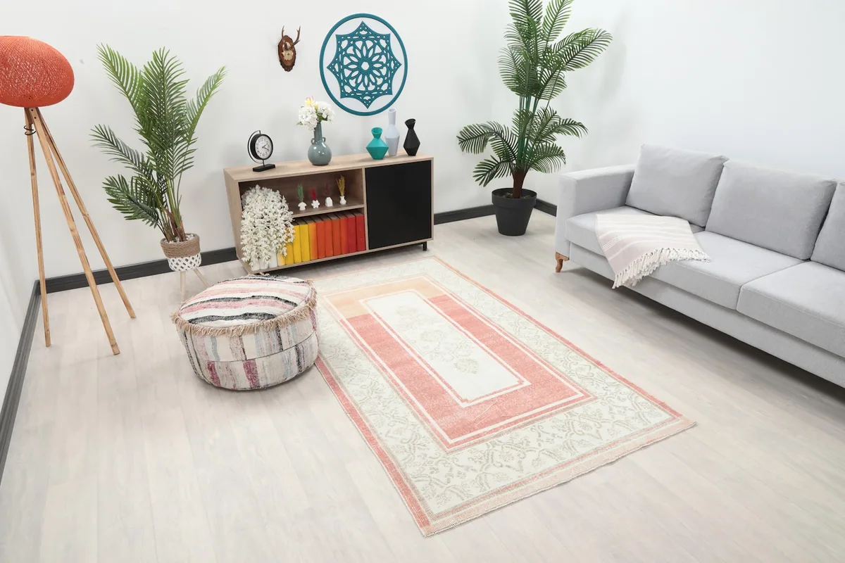 Angled view of the rose and ivory rug in a living room, highlighting its colors and pattern.