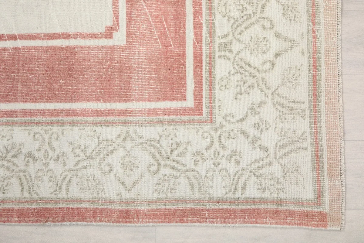 Detail of the rug's corner border, displaying the geometric and floral patterns in ivory and tan.
