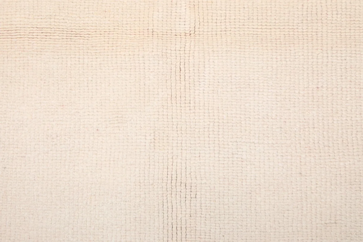 Close-up texture of the low wool pile on the rug's ivory surface