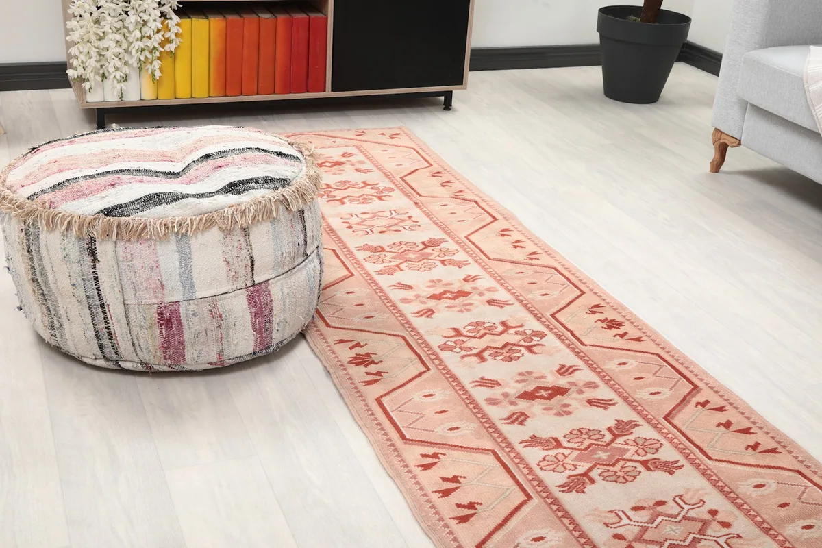 Close-up view of the rug's pattern in a room, with a decorative ottoman nearby