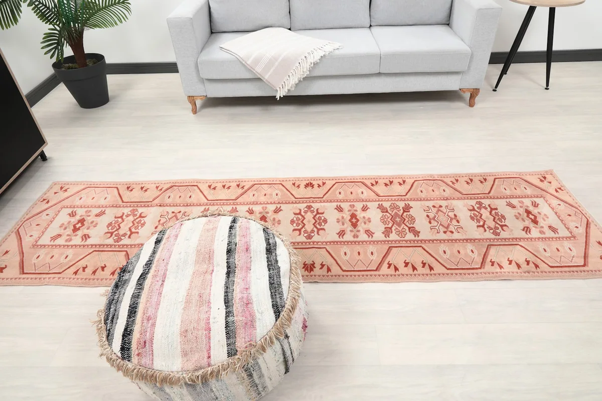 Full length of the runner rug in a room, with a sofa and ottoman, showcasing its scale