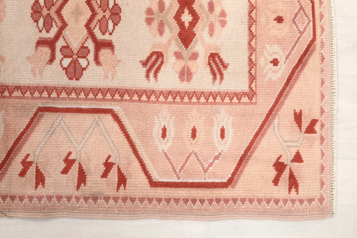 Detailed view of the rug's corner and border design, showing the intricate rose and cream patterns