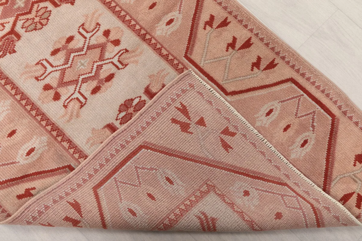 Folded corner of the rug revealing the cotton foundation and the reverse side of the pattern