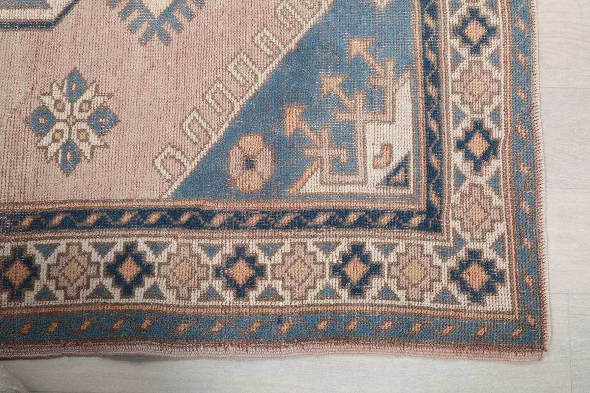 Detailed view of the rug's corner, highlighting the blue border and geometric patterns.