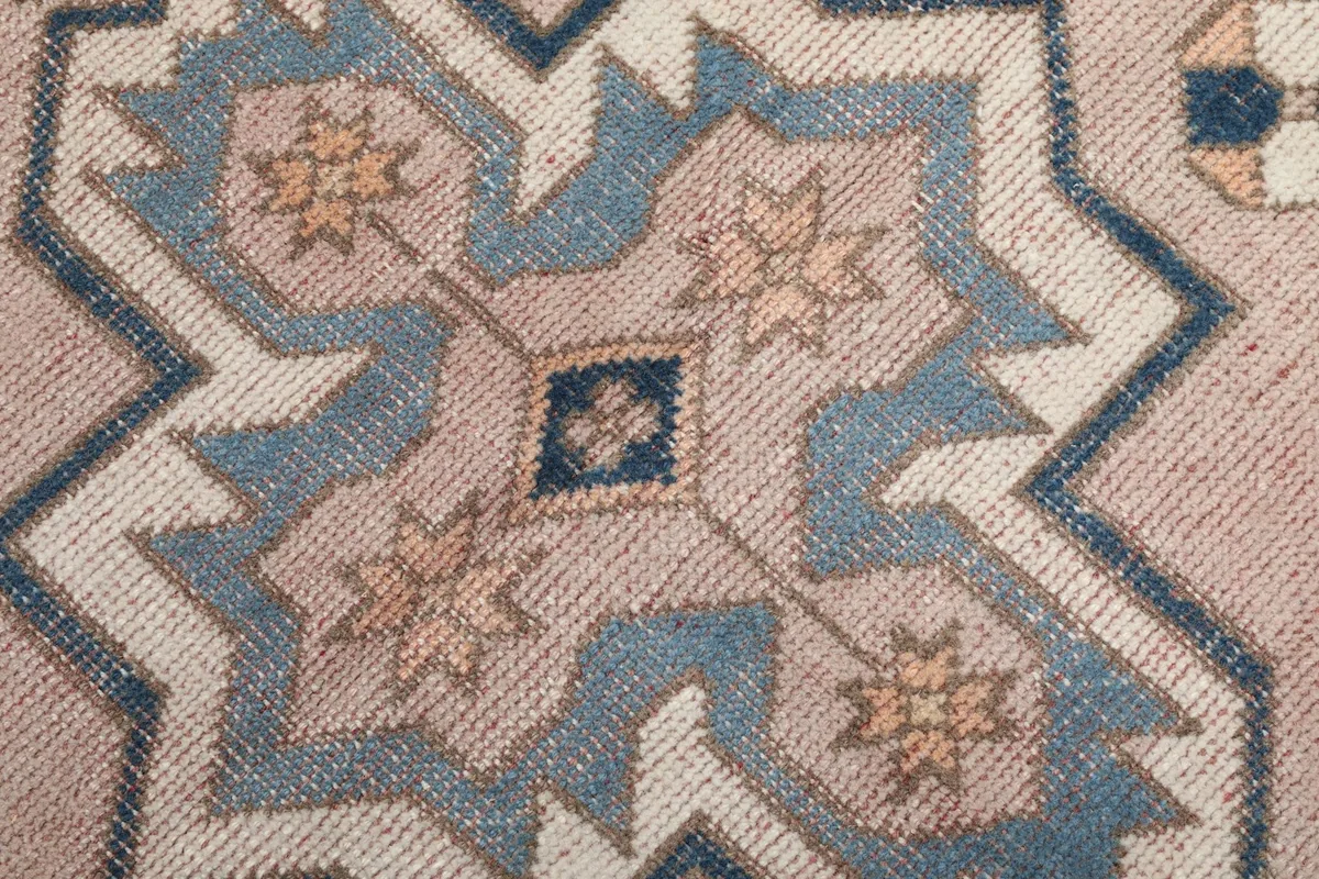Extreme close-up of the wool pile, revealing the texture and color variations of the vintage rug.