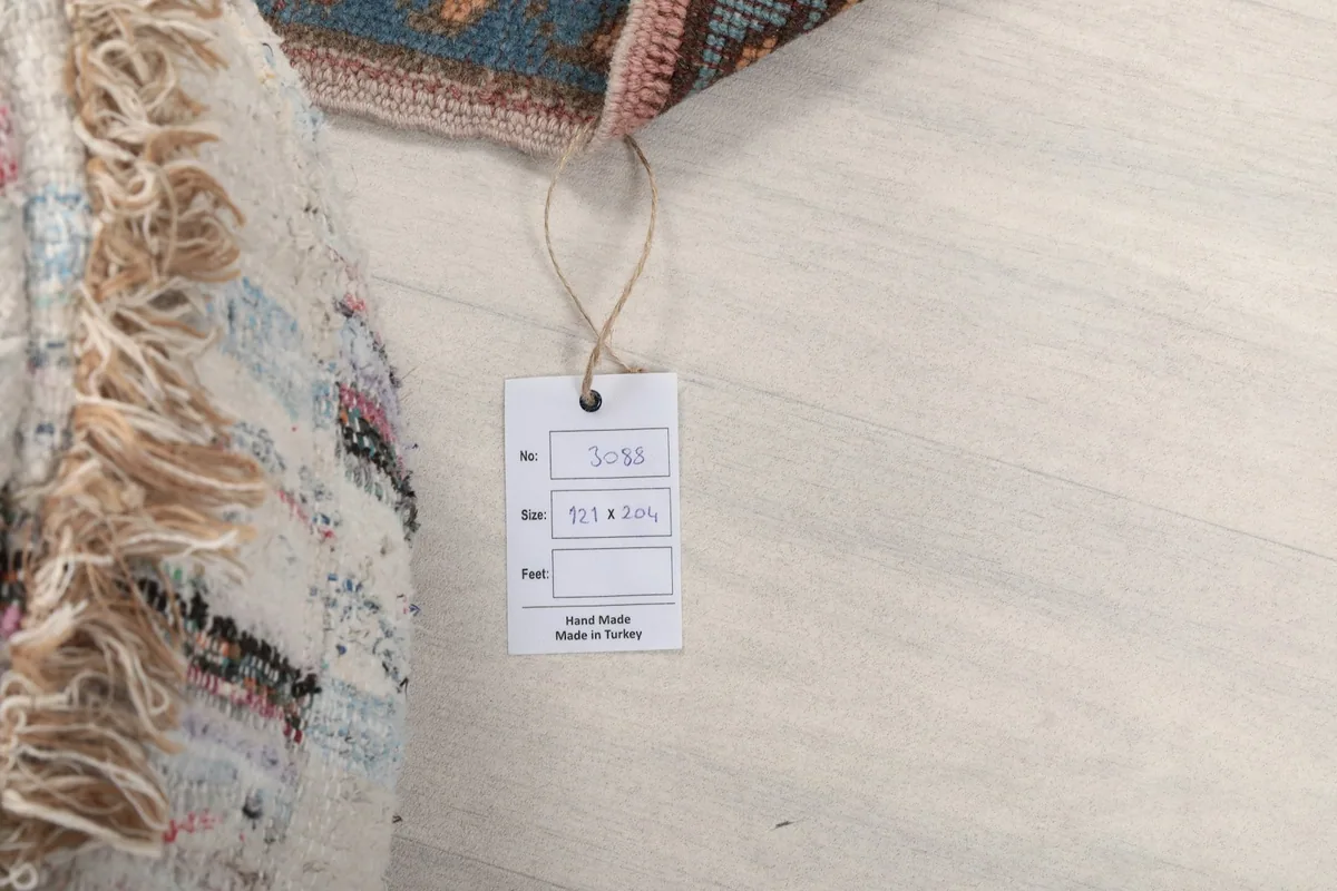 Product tag displaying the rug's size and origin, next to a decorative pouf.