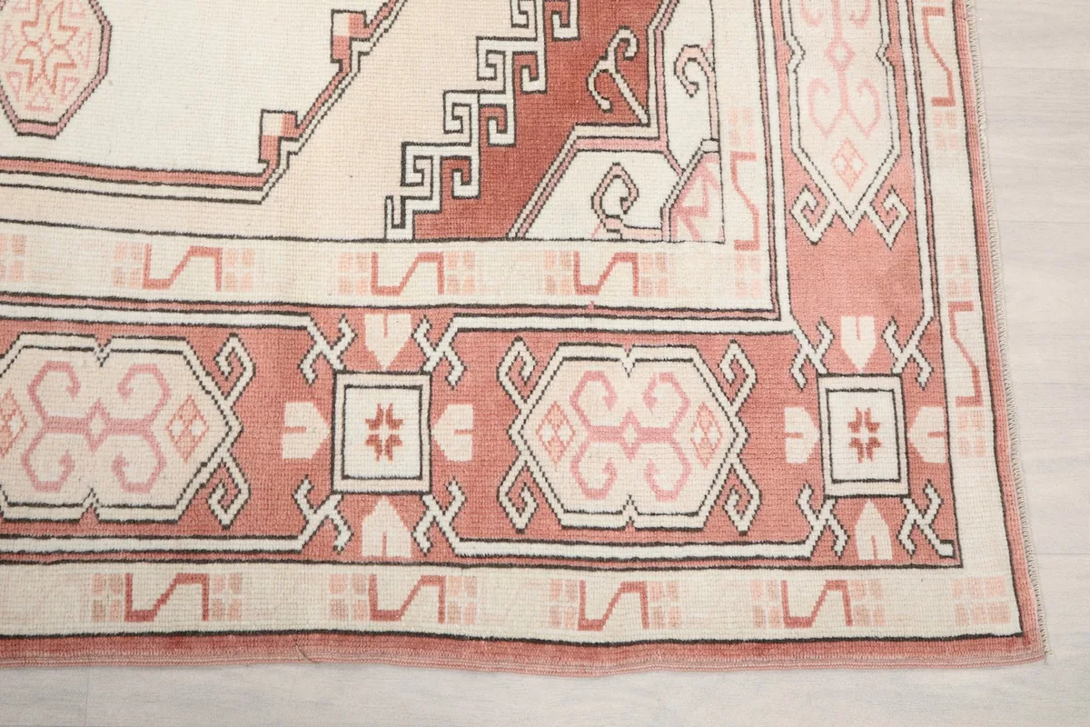 Detailed view of the rug's outer border with rose and beige tribal patterns
