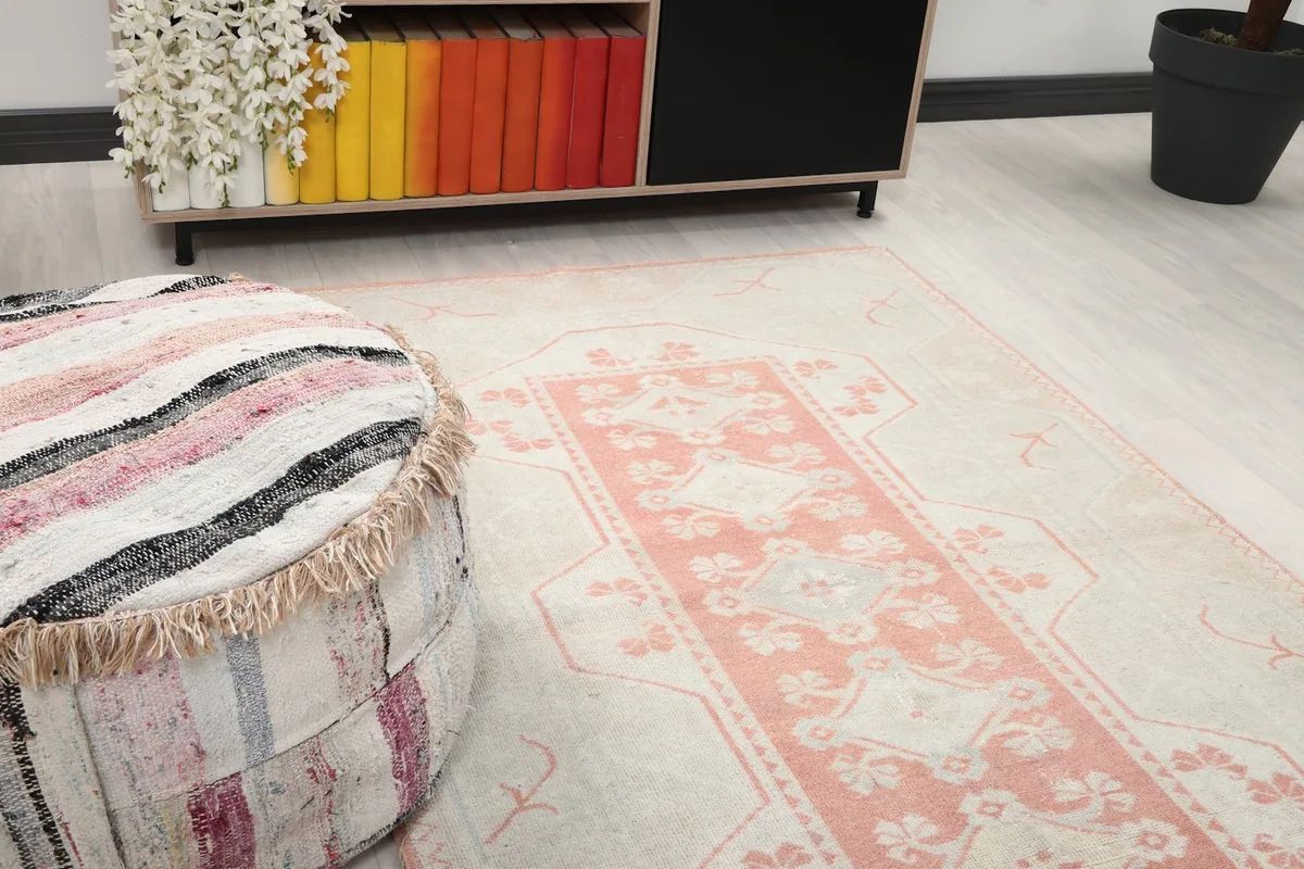 Close-up of the rug's pink medallion and cream field next to a striped pouf