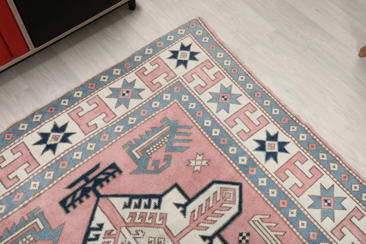 Corner view of the rug, showing the blend of rose, blue, and ivory tones