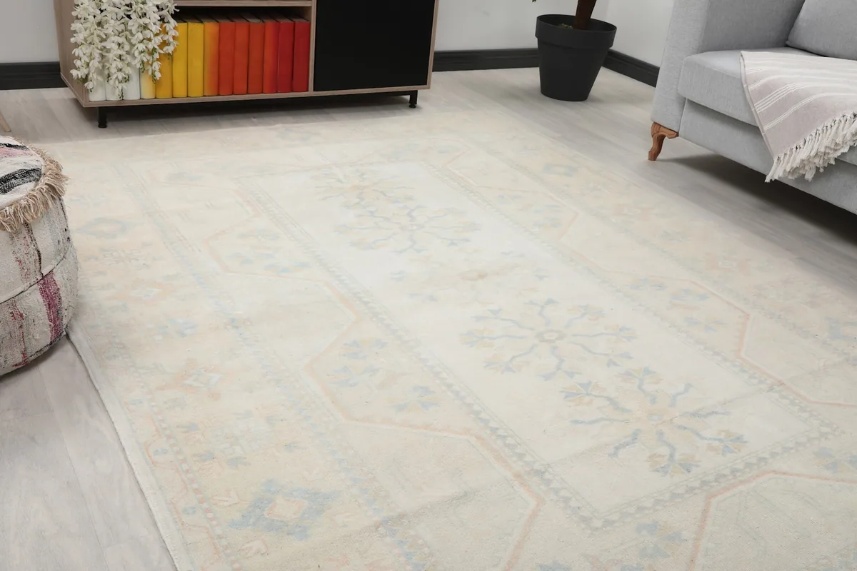 Close-up angle showing the ivory field and faded blue and tan motifs of the rug