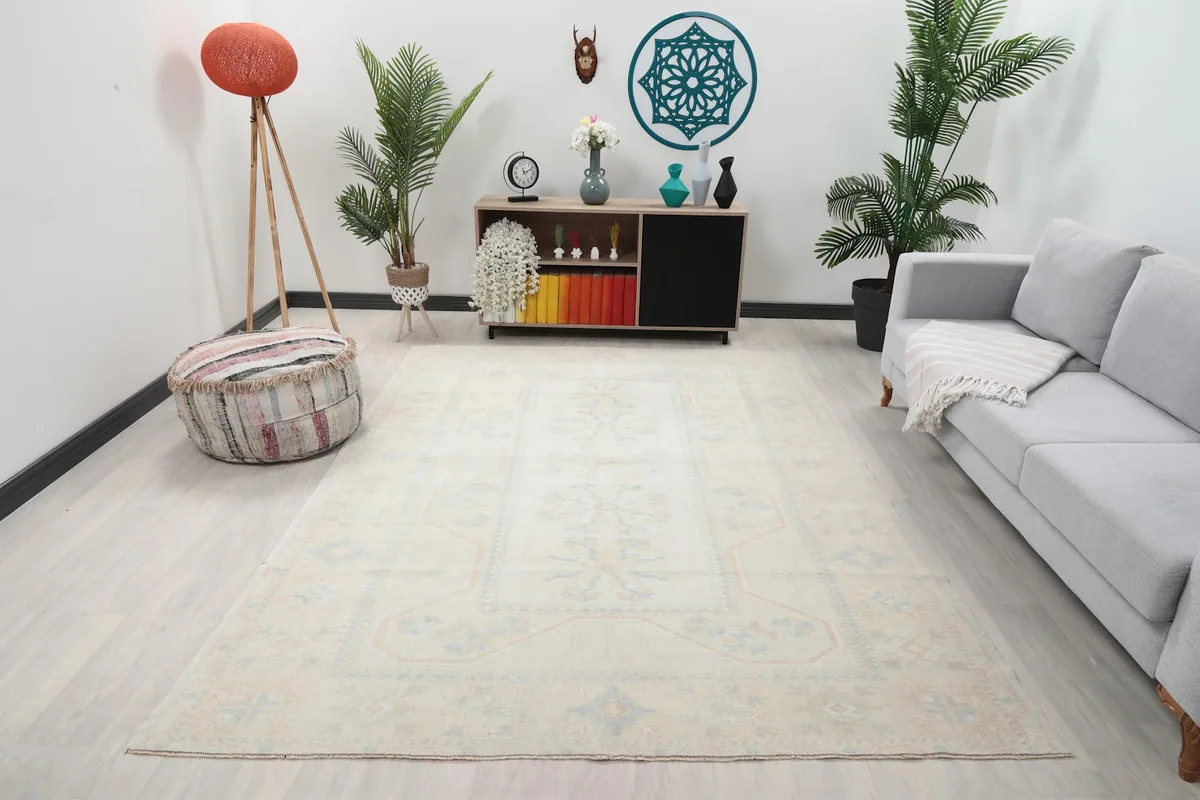 Vintage ivory rug displayed in a bright room setting with a sofa and decor