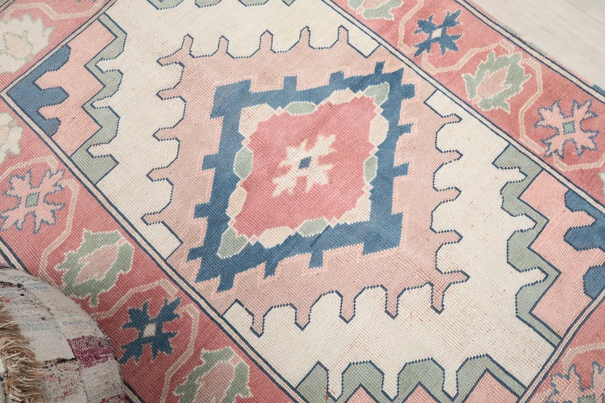 Angled view highlighting the ivory field and the prominent rose and blue geometric medallion