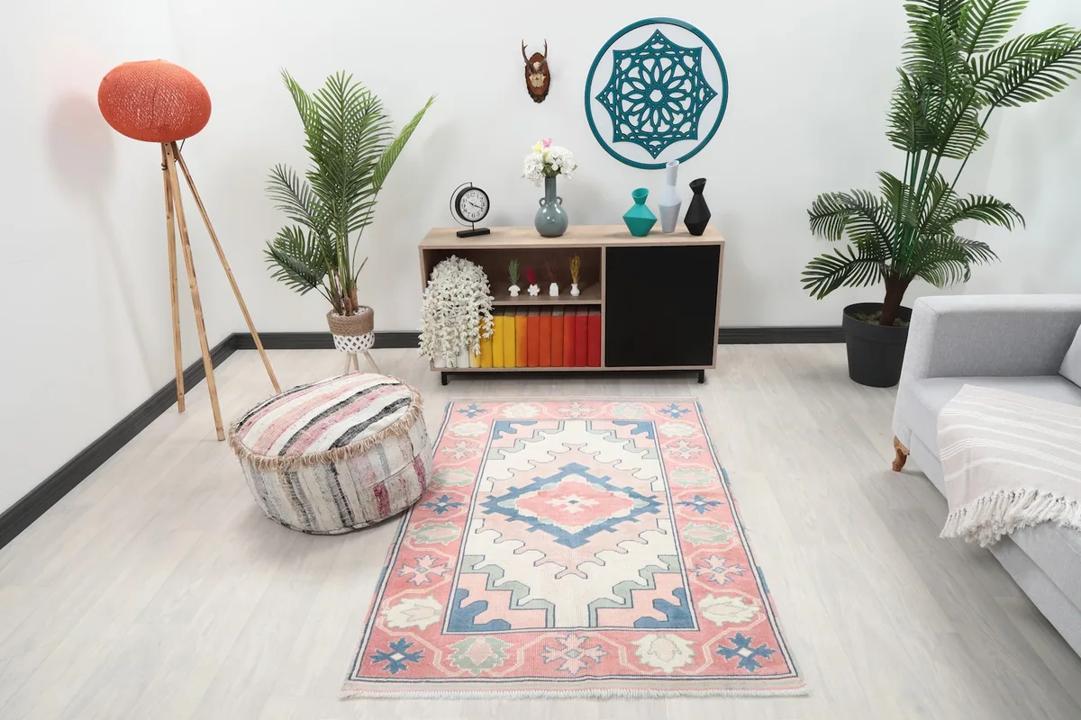 Rose and ivory geometric rug displayed in a modern living room setting with light furniture