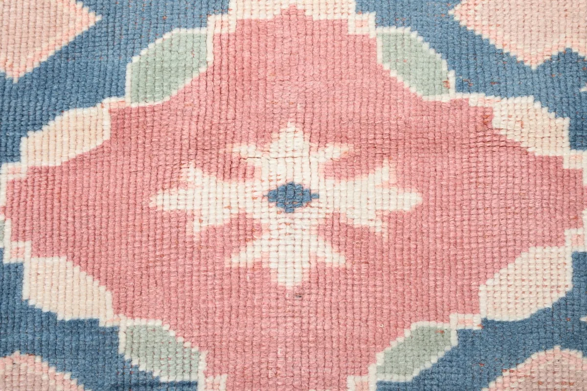 Close-up of the wool pile texture and knotting in the rose and blue central pattern