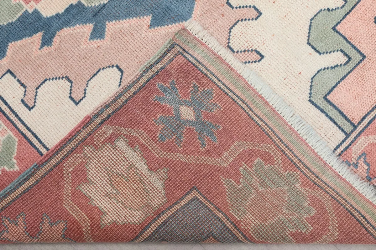 View of the underside of a rug corner, revealing the hand-knotted cotton foundation