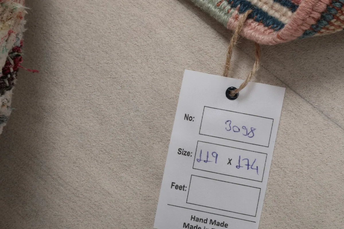 Close-up of the product tag showing the rug's dimensions and handmade origin