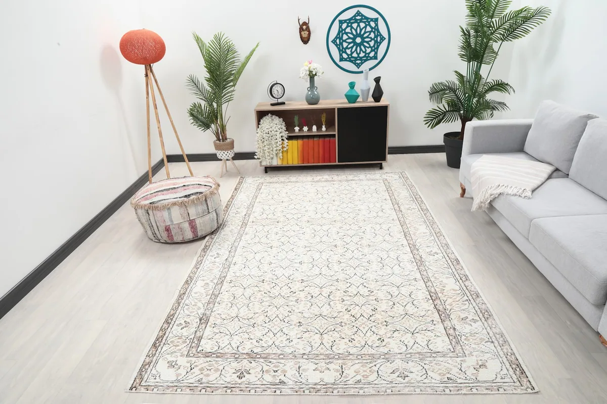 Vintage ivory rug displayed in a bright living room setting with a gray sofa
