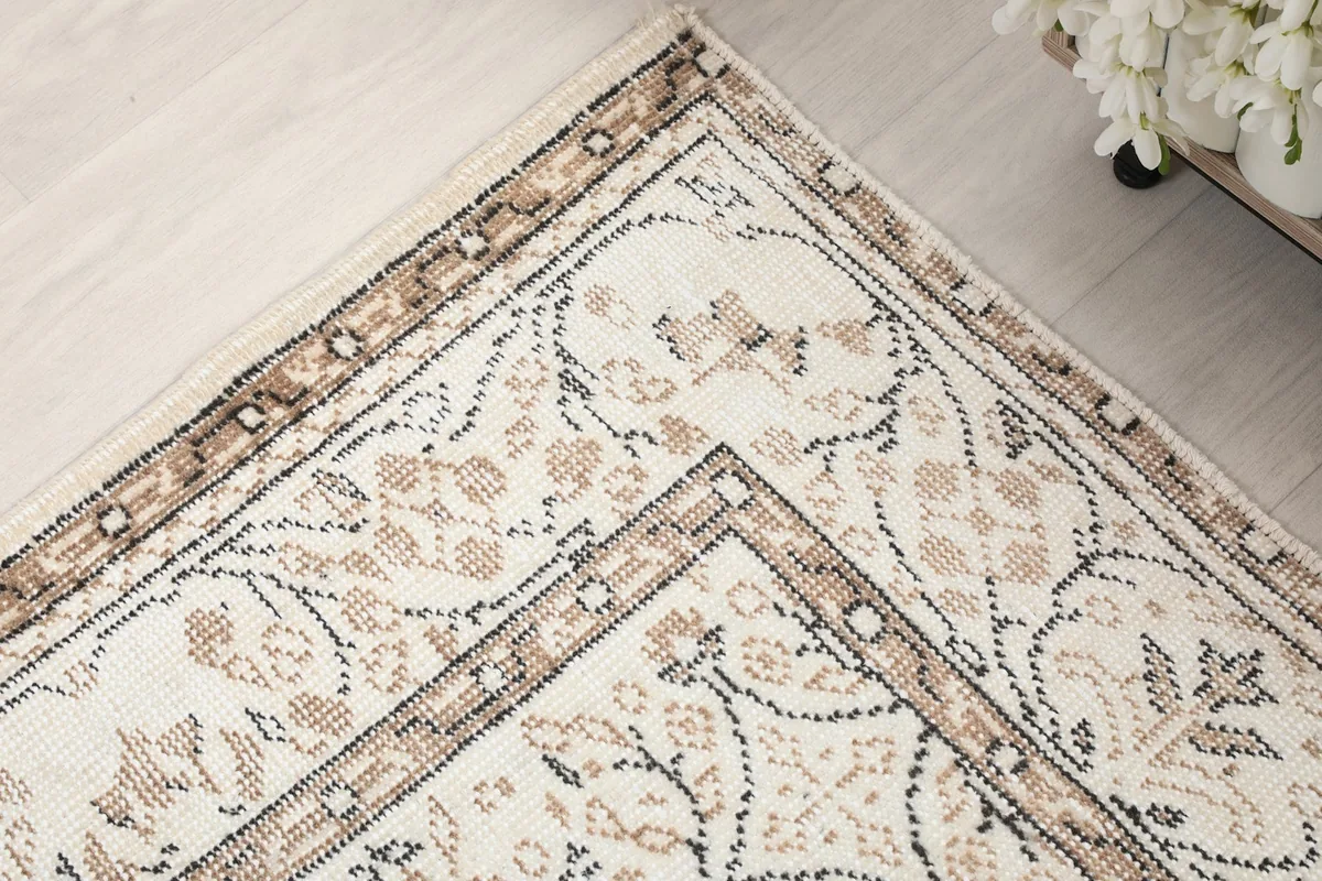 Close-up of the rug's border design and corner, featuring brown and tan floral elements
