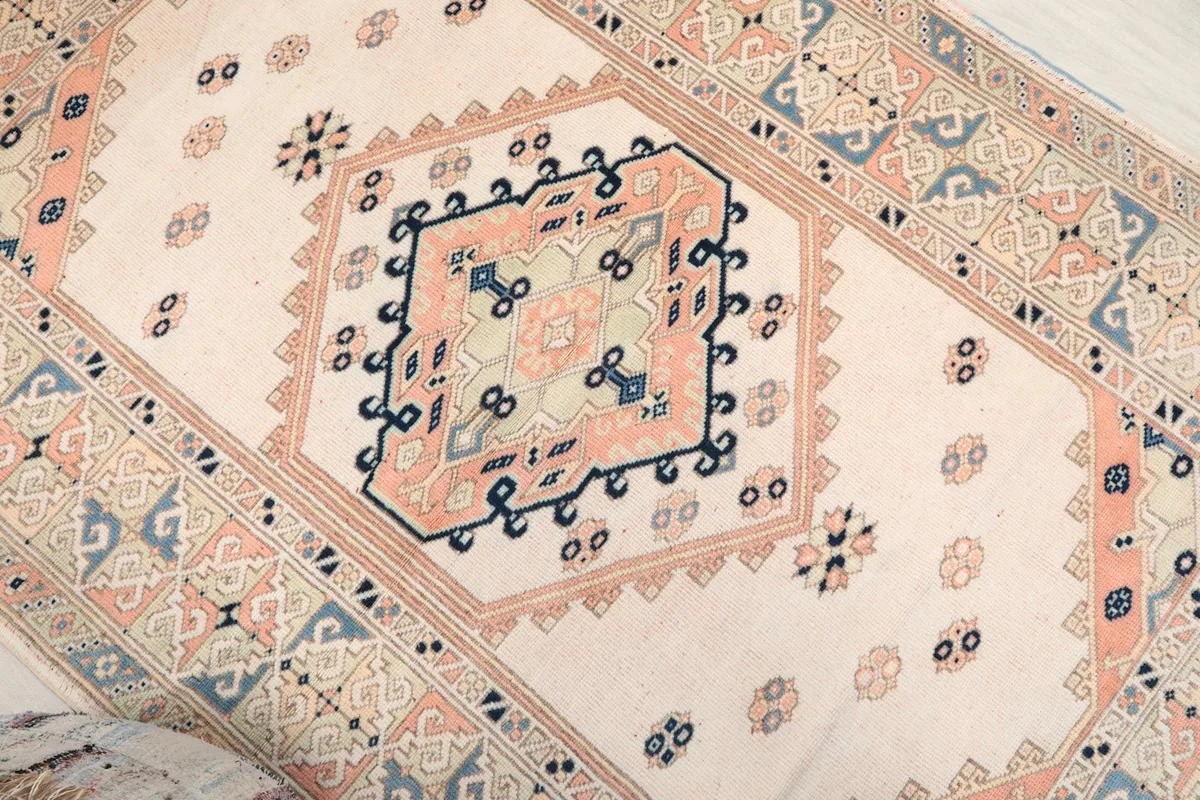 Overhead close-up of the central tribal medallion with rose, navy, and light blue details