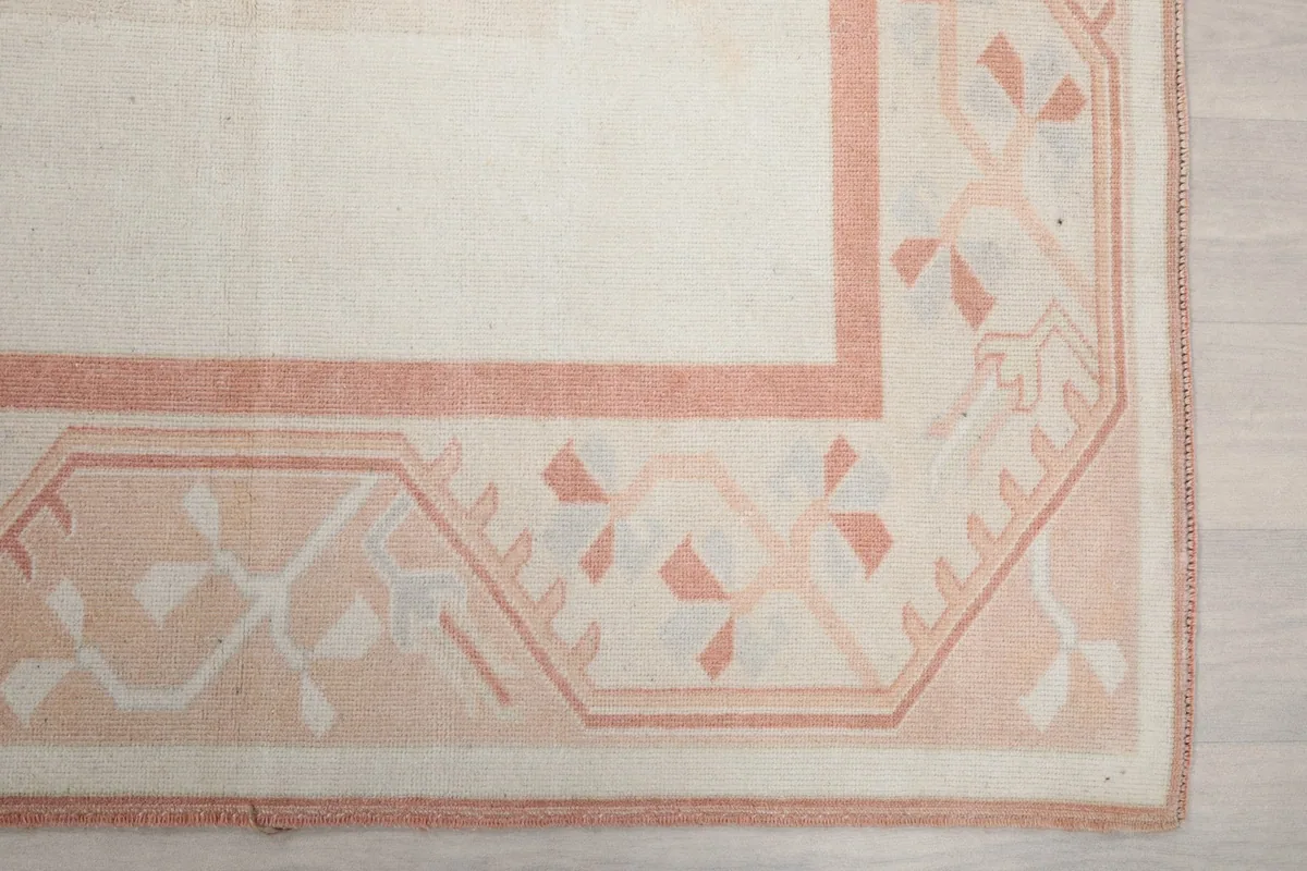 Detail of the geometric rose-colored border pattern on the vintage rug
